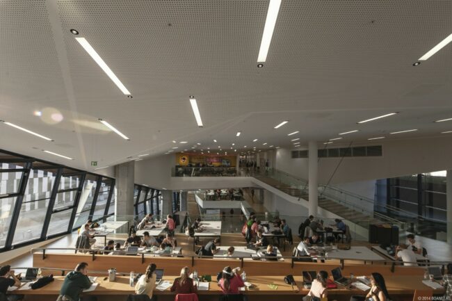 WU-Wien-Lernzonen. Viele lernende Studierende sitzend auf Holzbänken.