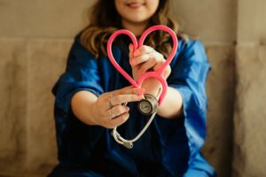 Krankenschwester Ausbildung – Frau formt Herz mit rotem Abhörgerät
