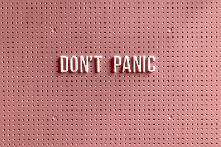 Eine rosarote Pinnwand, auf der in weißen Großbuchstaben Don't Panic steht